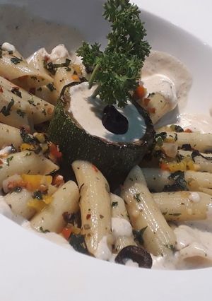 A picture of Penne aglio olio with backed zucchini and cheese mushroom sauce.