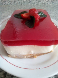 Una foto de Panna cotta con base de galletas y sirope de fresas