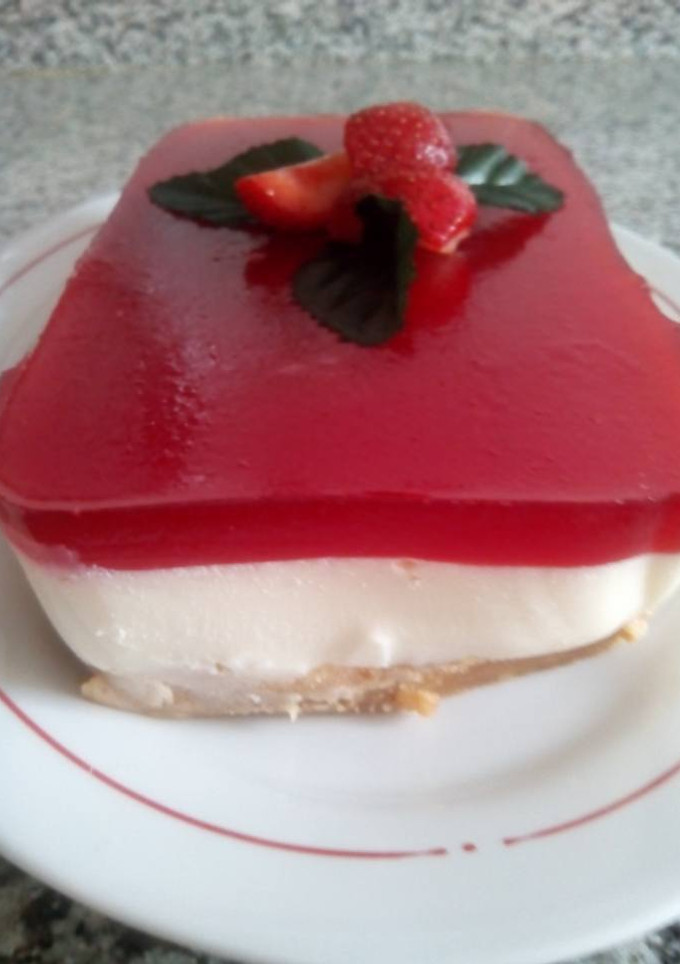 Una foto de Panna cotta con base de galletas y sirope de fresas