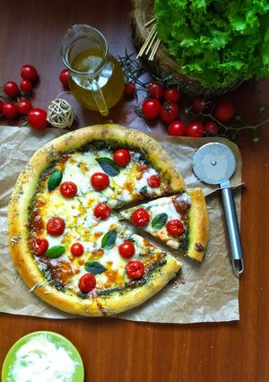 Une photo de Pizza à la sauce pesto et aux tomates cerises