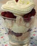 Postre de merengue, crema y frambuesas en vaso
