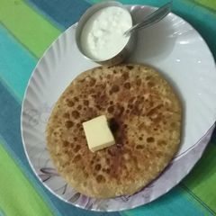 A picture of Aaloo parantha, butter and dahi.
