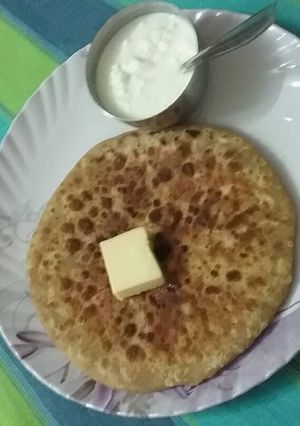 A picture of Aaloo parantha, butter and dahi.