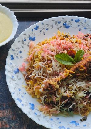 A picture of Smokey tandoori chicken drumsticks biryani with mint mango raita.