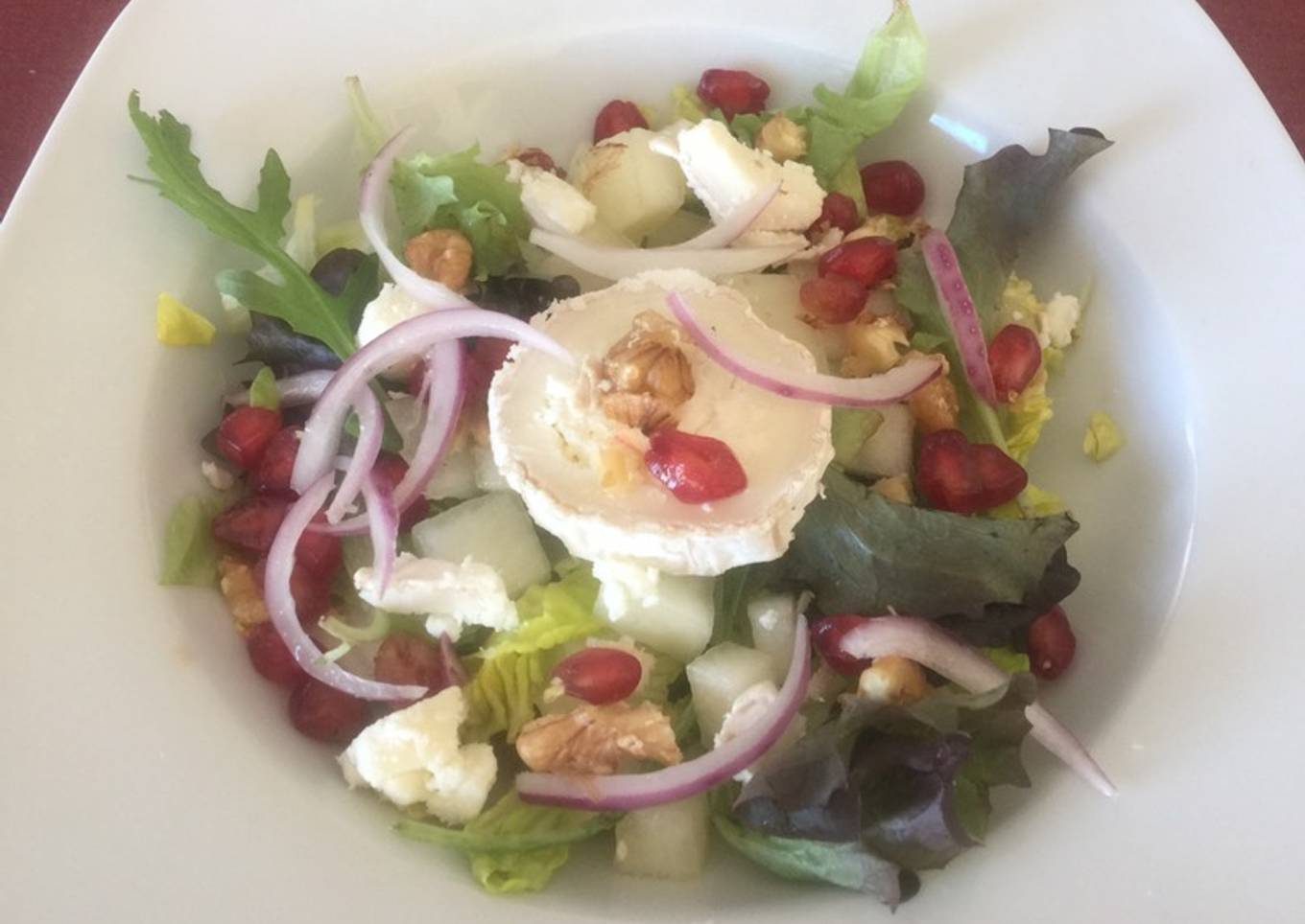 Ensalada con queso de cabra, melón, granos de granada y cebolla