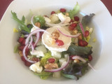 Ensalada con queso de cabra, melón, granos de granada y cebolla