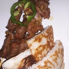 A picture of Rice pancakes with roasted beef on skewers.