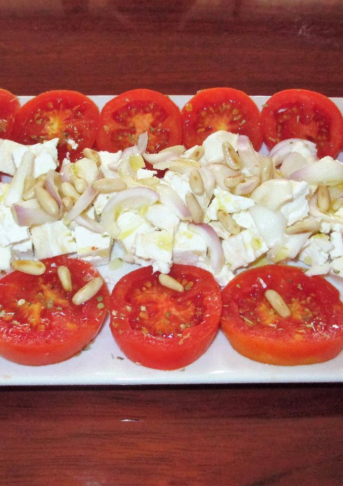 Una foto de Ensalada de tomates con queso y piñonesal orégano