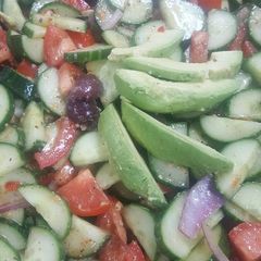 A picture of Greek tomato and cucumber salad with avocados.
