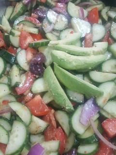 A picture of Greek tomato and cucumber salad with avocados.