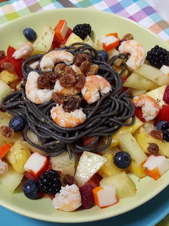 Una foto de Espaguetis negros con frutas y gambas