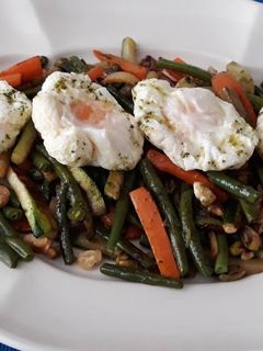 Una foto de Verdura salteada con frutos secos y huevo poché