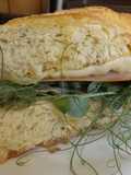 Bocadillo de pan de maíz con jamón, quesos y brotes