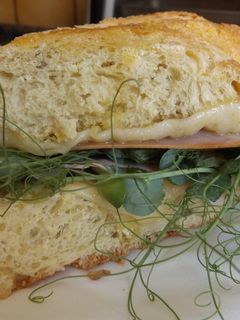 Una foto de Bocadillo de pan de maíz con jamón, quesos y brotes