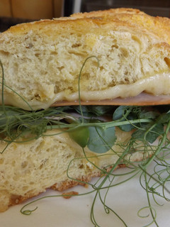Una foto de Bocadillo de pan de maíz con jamón, quesos y brotes
