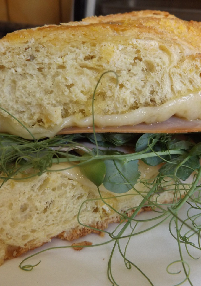 Una foto de Bocadillo de pan de maíz con jamón, quesos y brotes