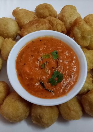 A picture of Urad daal pakoda with tomato onion chutney.