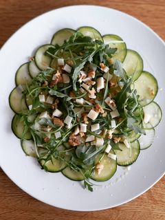 Una foto de Carpaccio de calabacín, parmesano y rúcula con aceite de albahac