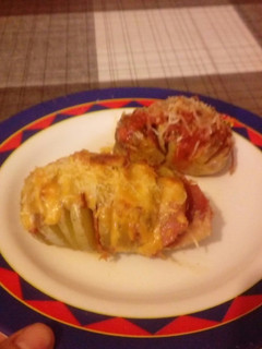 Una foto de Patatas gratinadas con jamón queso salsa boloñesa y salsa brava