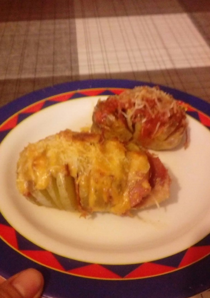 Una foto de Patatas gratinadas con jamón queso salsa boloñesa y salsa brava