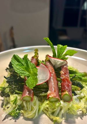 A picture of Cabbage&fennel vinaigrette topped with spiced broccolini and prosciutto wrapped asparagus.
