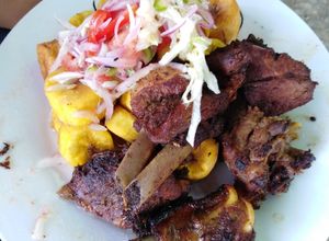 Una foto de Fritada de cerdo con ensalada CRIOLLA y patacones