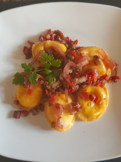 Una foto de Sorrentinos, con vegetales y salsa en vino tinto