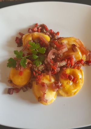 Una foto de Sorrentinos, con vegetales y salsa en vino tinto