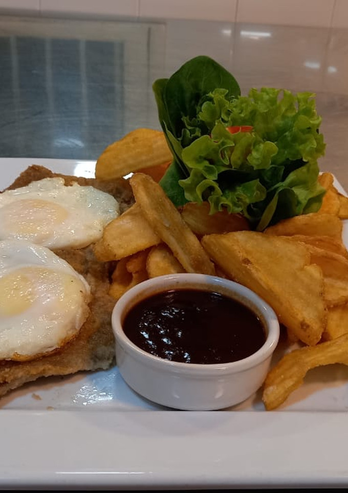 Una foto de Milanesa con huevos fritos y papas fritas