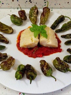 Una foto de Bacalao con salsa de tomate y pimientos de padrón fritos