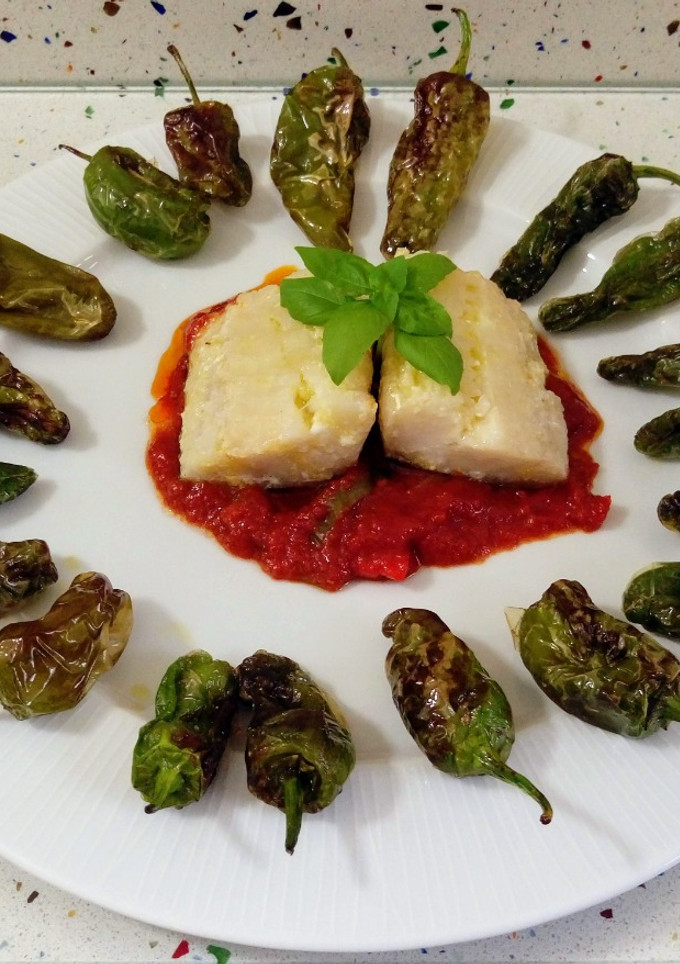 Una foto de Bacalao con salsa de tomate y pimientos de padrón fritos