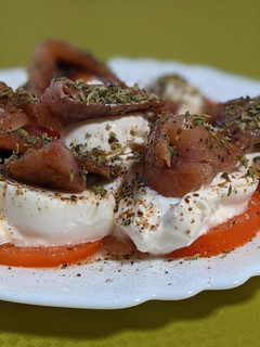 Una foto de Aperitivo de tomate con burrata y sardina ahumada en madera de haya