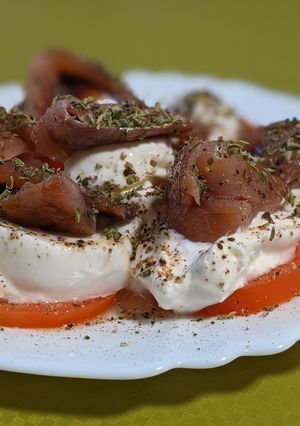 Una foto de Aperitivo de tomate con burrata y sardina ahumada en madera de haya