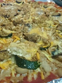 Una foto de Pizza de tomate frito, calabacín, berenjena, queso rulo de cabra, champiñones y atún