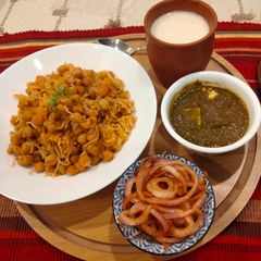 A picture of Punjabi thali (chole with rice, creamy Palak paneer, spicy onion lachcha and refreshing lassi).