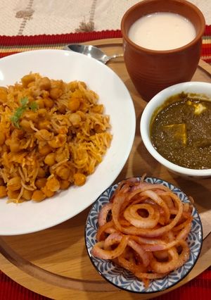 A picture of Punjabi thali (chole with rice, creamy Palak paneer, spicy onion lachcha and refreshing lassi).