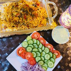 A picture of Biryani with colourful salad.