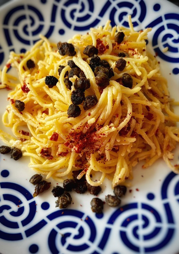 Una foto de Spaghetti picante con cremoso de tomate seco y alcaparras crujientes