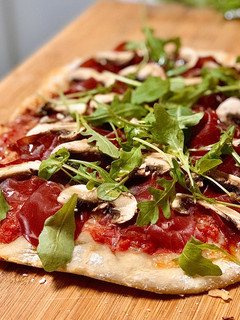Una foto de Pizza casera con bresaola y rúcula