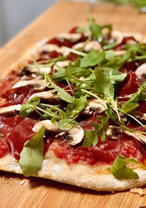 Una foto de Pizza casera con bresaola y rúcula