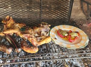 Una foto de Pierna de cordero a la parrilla, acompañada de morrones rellenos de jamón, muzarella y huevo