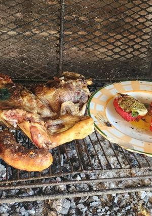Una foto de Pierna de cordero a la parrilla, acompañada de morrones rellenos de jamón, muzarella y huevo