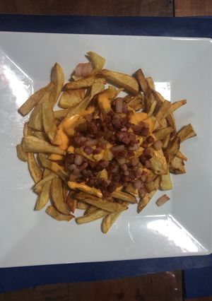 Una foto de Papas fritas con cheddar y panceta