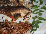 A picture of fried fish with fried tomatoes