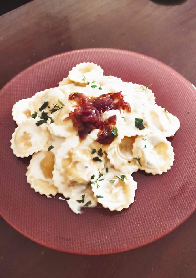 Una foto de Raviolis mozzarella, salsa de queso azul y cebolla caramelizada