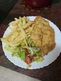Pechuga de pollo rebozada y frita con papas fritas y ensalada