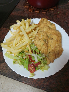 Una foto de Pechuga de pollo rebozada y frita con papas fritas y ensalada