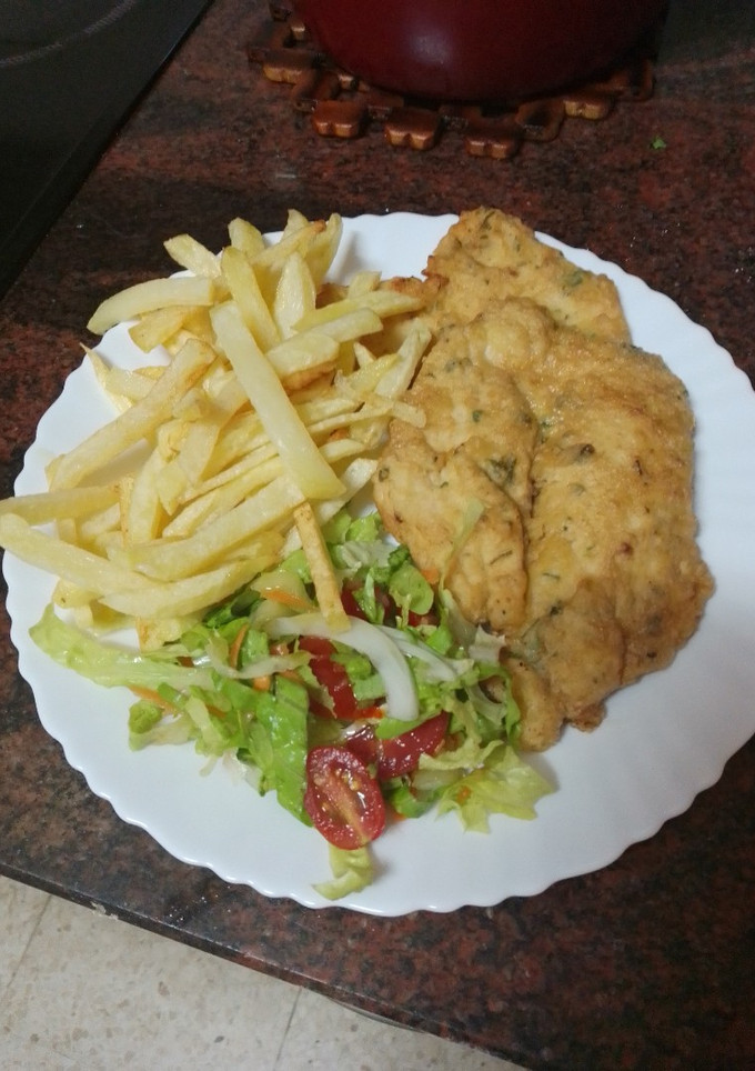 Una foto de Pechuga de pollo rebozada y frita con papas fritas y ensalada