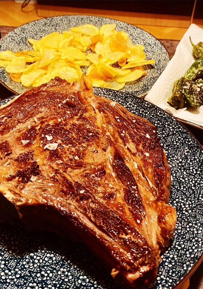 Una foto de Chuleta de vaca gallega madurada, con patatas y pimientos de Padrón