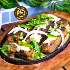 A picture of Makhmali Mutton Malayi Sizzler Seenkh Kabaab With White Creamy Gravy.
